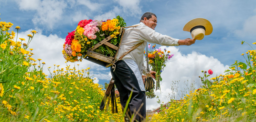 Silletero con una silleta de flores coloridas en un jardín de Medellín